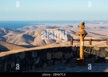 Observation deck with a coin-operated telescope overlooking a barren hilly landscape, Fuerteventura, Canary Islands, Spain Stock Photo