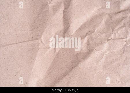 Old wrinkled brown craft paper poster texture. Blank creased crumpled grainy beige kraft paper textured surface. Smudged grungy cardboard with fibers. Stock Photo
