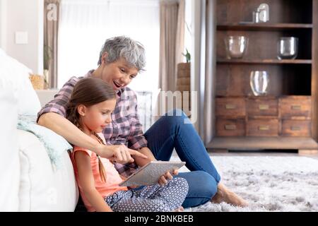 Senior Caucasian woman using a tablet at home with her granddaughter Stock Photo