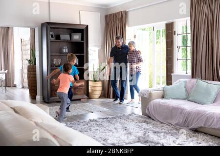 Caucasian girl and boy welcoming their grandparents entering their house. Stock Photo
