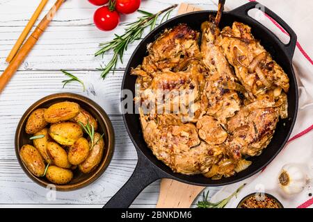 Fried Rabbit Meat With Rosemary in Sour Cream Sauce and Potato on White Wooden Background Stock Photo