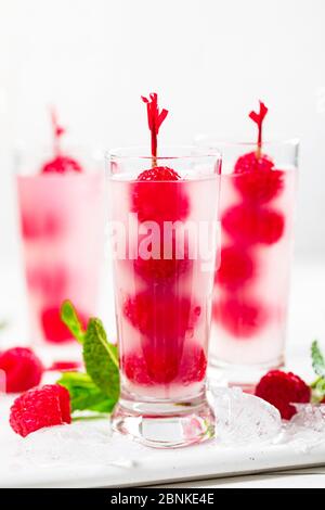 Raspberry Vodka Shots Lemonade Cocktail with Fresh Raspberry on White Wooden Background. Stock Photo