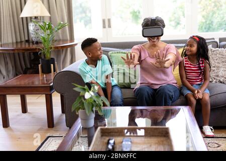 Senior mixed race woman and her grandchildren at home using VR headset Stock Photo