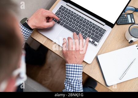 Businessman's hands typing on a computer keyboard during a home office. Man wearing casual shirt using laptop in the home. Office equipment such as no Stock Photo
