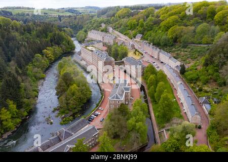 Aerial view of New Lanark World Heritage Site closed during covid-19 lockdown, beside River Clyde in South Lanarkshire, Scotland, UK