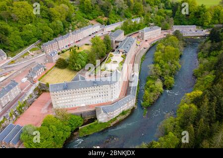 Aerial view of New Lanark World Heritage Site closed during covid-19 lockdown, beside River Clyde in South Lanarkshire, Scotland, UK