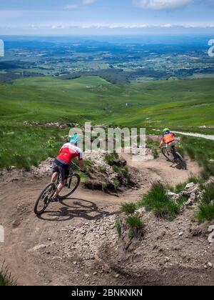 Mountain bikers near the village of Super Besse, descent in the bike park of Superbesseim Massif Central, in the Auvergne in France. Departure near the Puy de Sancy Stock Photo