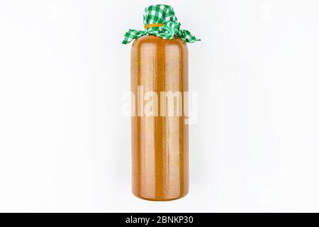 A brown, clay bottle closed with a green and white fabric with an elastic band, isolated on a white background with a clipping path. Stock Photo