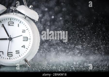 white retro alarm clock in a black background under the water drops.. Morning. Break. Motivation. Business solutions. Success. Deadline. Stock Photo