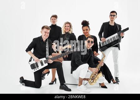 Multiracial music band on a white background. A group of international musicians rehearsing a concert performance. Vocalist, ram, guitarist