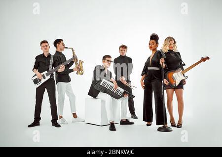 Multiracial music band on a white background. A group of international musicians rehearsing a concert performance. Vocalist, ram, guitarist