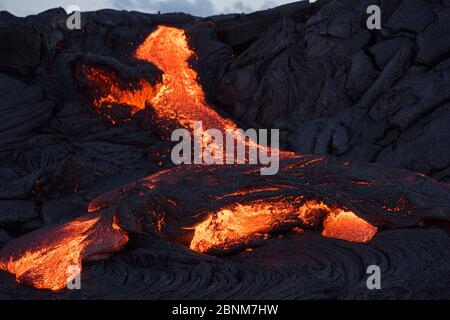 Pahoehoe lava from the 61G flow, emanating from Pu'u O'o on Kilauea Volcano, oozes from a breakout near the  Kamokuna ocean entry in Hawaii Volcanoes Stock Photo