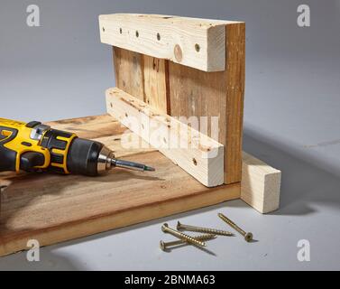 Construction of a shelf made of wood, Euro pallet, solid wood, MDF board; Do-it-yourself production, step-by-step, step 5 connecting the elements with screws, cordless screwdriver Stock Photo