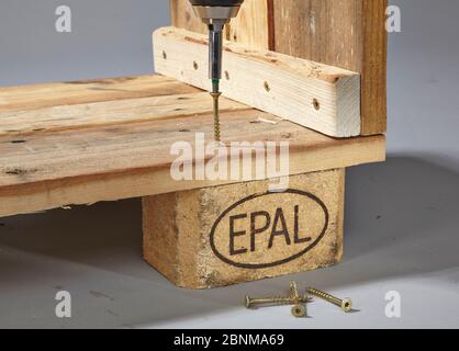 Construction of a shelf made of wood, Euro pallet, solid wood, MDF board; Do-it-yourself production, step-by-step, step 6b: screwing on the blocks with the cordless screwdriver and wood screws Stock Photo