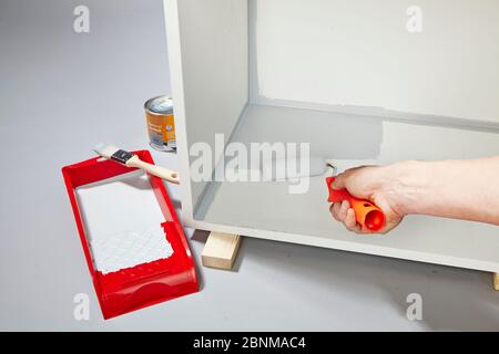 Construction of a shelf made of wood, Euro pallet, solid wood, MDF board; Do-it-yourself production, step-by-step, step 14, top coat with light gray acrylic paint and foam roller Stock Photo
