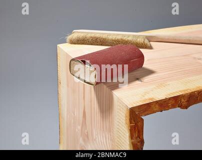 Building a wooden shelf, do-it-yourself production, step-by-step, step 16, sanding the outer edge after the glue has hardened using a sanding block, removing sanding dust with a dust brush Stock Photo