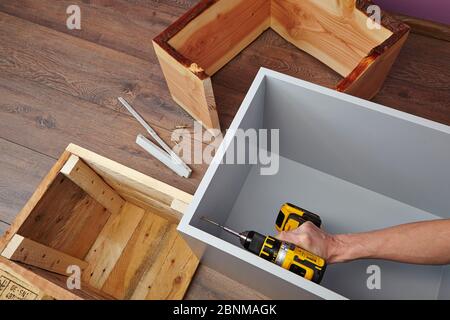 Construction of a shelf made of wood, Euro pallet, solid wood, MDF board; Do-it-yourself production, step-by-step, step 19, screwing together the individual furniture elements Stock Photo