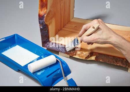 Building a wooden shelf, do-it-yourself production, step-by-step, step 17d painting the finished glued furniture with water-soluble acrylic paint, first painting the corners with a brush, then painting the surfaces with a foam roller Stock Photo