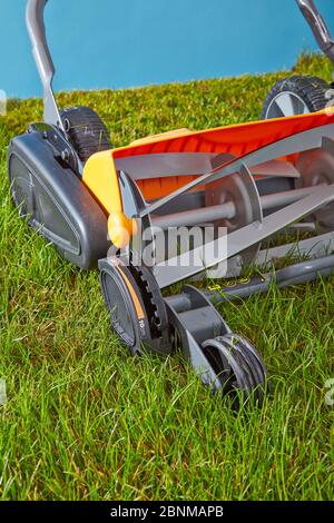 Mowing the lawn by hand. Symbolic photo, spindle mower on lawn against light blue, sky Stock Photo