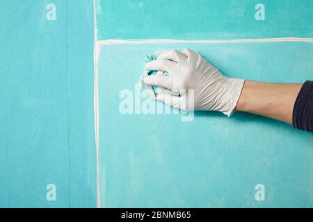DIY wall design 02, step-by-step do-it-yourself production, various turquoise colored areas separated by white wooden strips, step 04: watering the individual areas with a damp cloth, wiping off excess paint Stock Photo