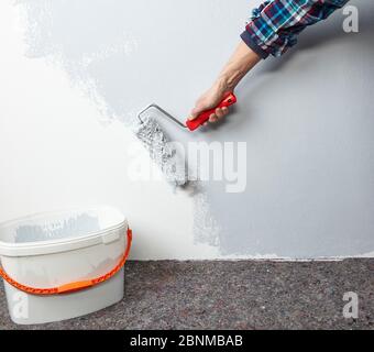 DIY wall design 03, step-by-step do-it-yourself production, various colored areas with wall paint and roller plaster, gray and yellow, Step 1: painting a part of the wall with light gray wall paint and a paint roller Stock Photo