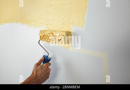 DIY wall design 03, step-by-step do-it-yourself production, various colored areas with wall paint and roller plaster, gray and yellow, step 4: painting the taped areas with roller plaster and paint roller Stock Photo