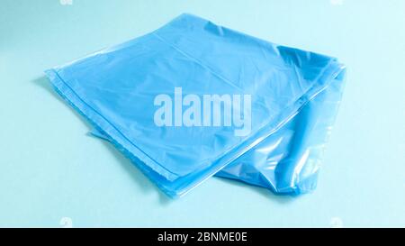 One torn plastic garbage bag in blue on a blue background. A bag that is designed to accommodate garbage in it and is used at home and placed in vario Stock Photo