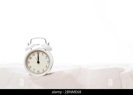 Alarm clock in sand on beach. Vacation time concept Stock Photo