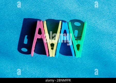 pink, yellow, red and blue plastic clothes pins on blue background. Top view and copy space Stock Photo