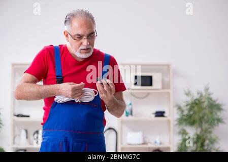 Old repairman repairing appliances in his workshop Stock Photo