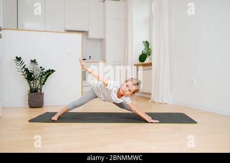 Six year old girl doing yoga at home, bending forward with legs wide apart Stock Photo