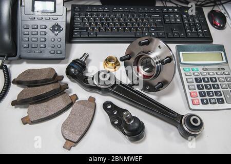 car parts laid out on a table with a phone, a calculator and a computer keyboard at shallow depth of field Stock Photo