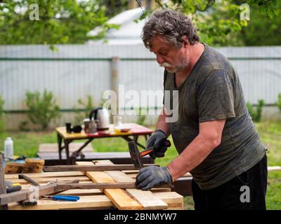 Mature Caucasian man hammering a nail into a board in a garden Stock Photo