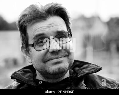 Black and white portrait of a friendly unshaven caucasian man with glasses Stock Photo