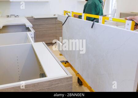 Workers lifting and installing with maple granite counter in kitchen cabinets Stock Photo