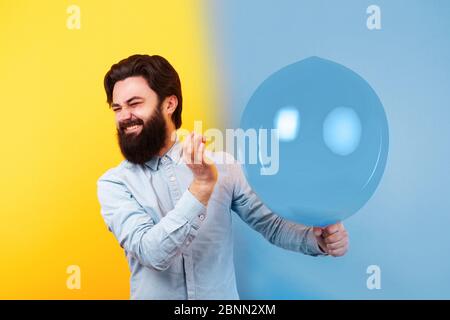 Man holding needle over yellow air balloon, a moment before bubble burst, toned image Stock Photo