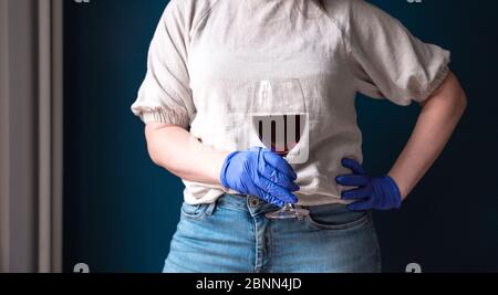 Woman wearing protective mask and blue gloves in her home and drinking red wine, self isolated for Coronavirus Covid-19, sad and lonely Stock Photo