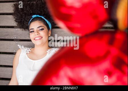 high angle view of a pretty girl lying down on a wooden background holding red balloons. Stock Photo