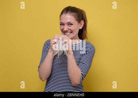 Caucasian laughing woman bursts bubbles on a packaging bubble wrap, calming down. Burst the bubbles with your fingers to relieve stress Stock Photo