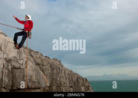 Female climber rappelling of seacliff in Swanage / England Stock Photo