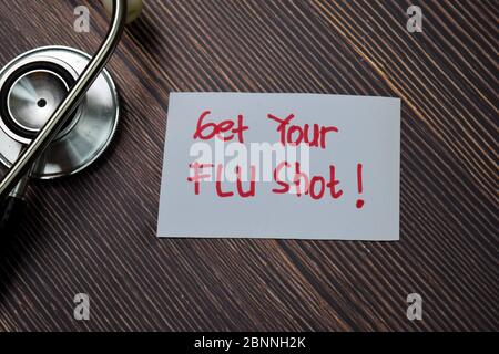 Get Your Flu Shot! write on sticky note isolated on wooden table. Stock Photo