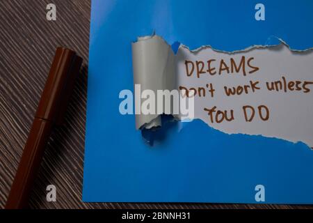 Dreams Don't Work Unless You Do Text written in torn paper. Stock Photo