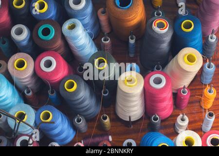 Colored thread on bobbins in a sewing workshop. Garment industry concept Stock Photo