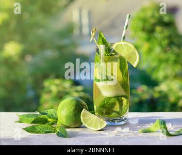 Lemonade or mojito cocktail with lime, cucumber and mint, cold refreshing drink or beverage with ice, outdoor.  Cold detox water with lemon and paper Stock Photo