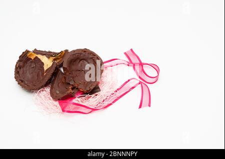 Homemade broken chocolate egg with red ribbon. Celebration of Easter, Mother's Day and Valentine's Day. Isolated on white background. Copy space. Stock Photo