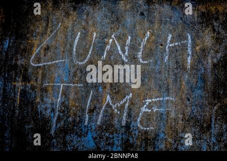 Lunch Time wrote on rough texture wall with white-colored chalk, horizontal shot. Stock Photo