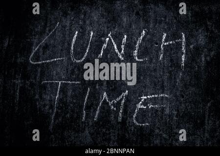 Lunch Time wrote on rough texture wall with white-colored chalk, horizontal shot. Stock Photo