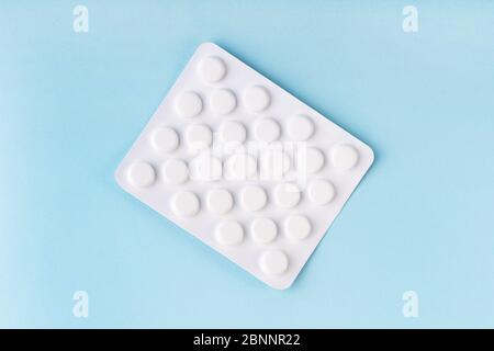 Tablets in blister, medicine on blue background. Pharmacy, healthcare concept. Coronavirus treatment. Drugstore concept. Tablet overdose. Stock Photo