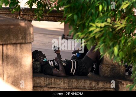 Milan, Italy - May 8, 2020: Bicyclist having rest under the tree. Man exercising outdoor wearing medical mask. Sport practice during coronavirus outbr Stock Photo