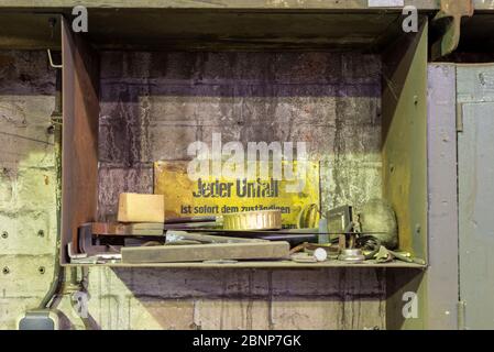 A look into a metal shelf with the warning sign 'Every accident must be reported immediately to the responsible health and safety officer'. Stock Photo